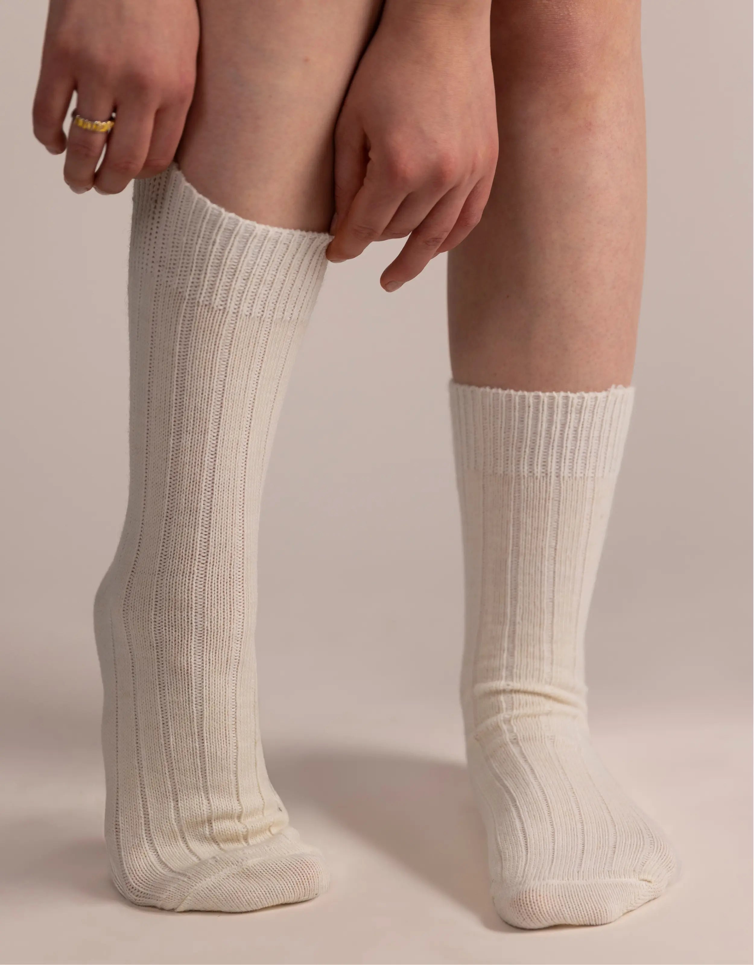 White knee-high socks worn by a person on a beige background