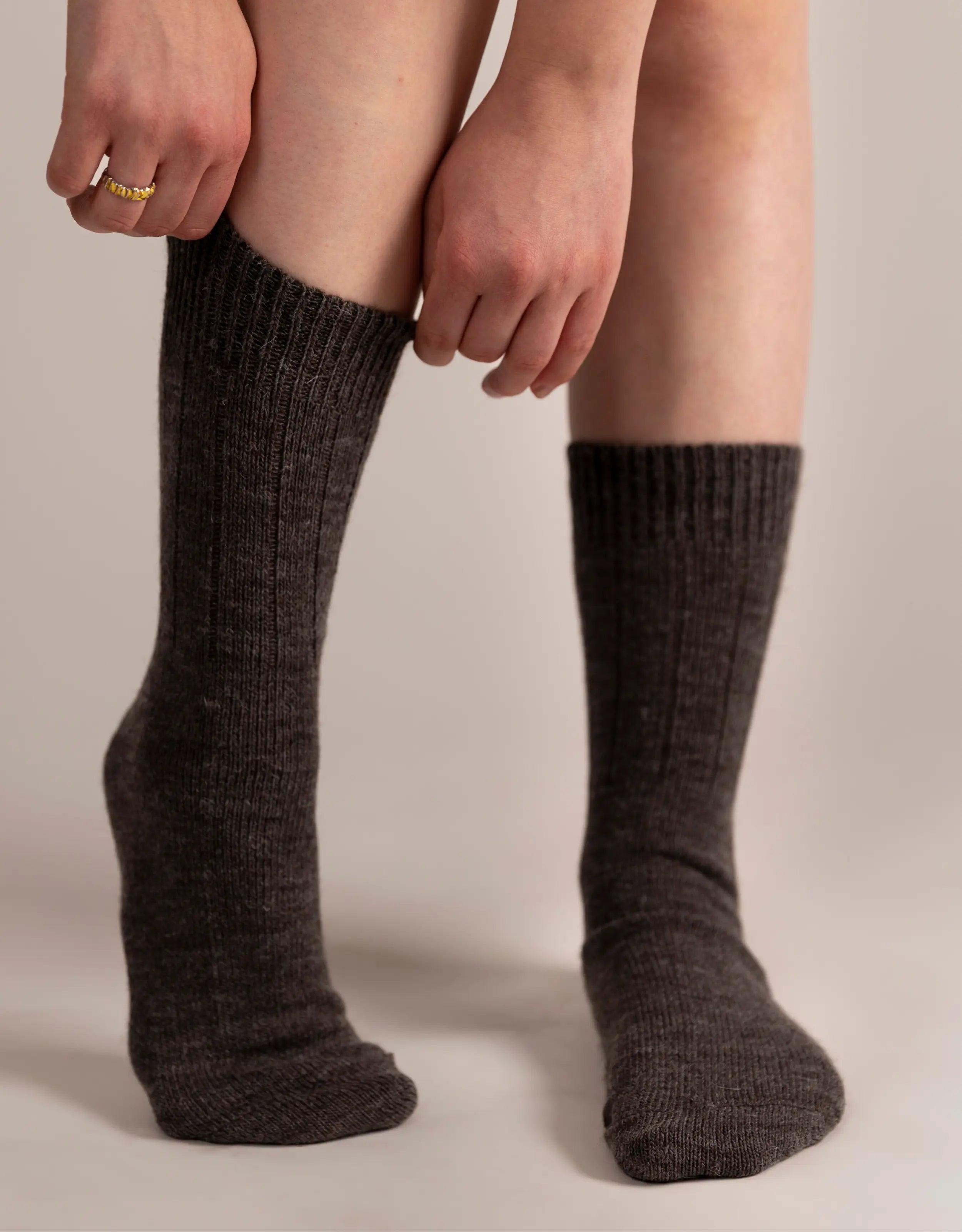 Person wearing dark brown knee-high socks on a plain background