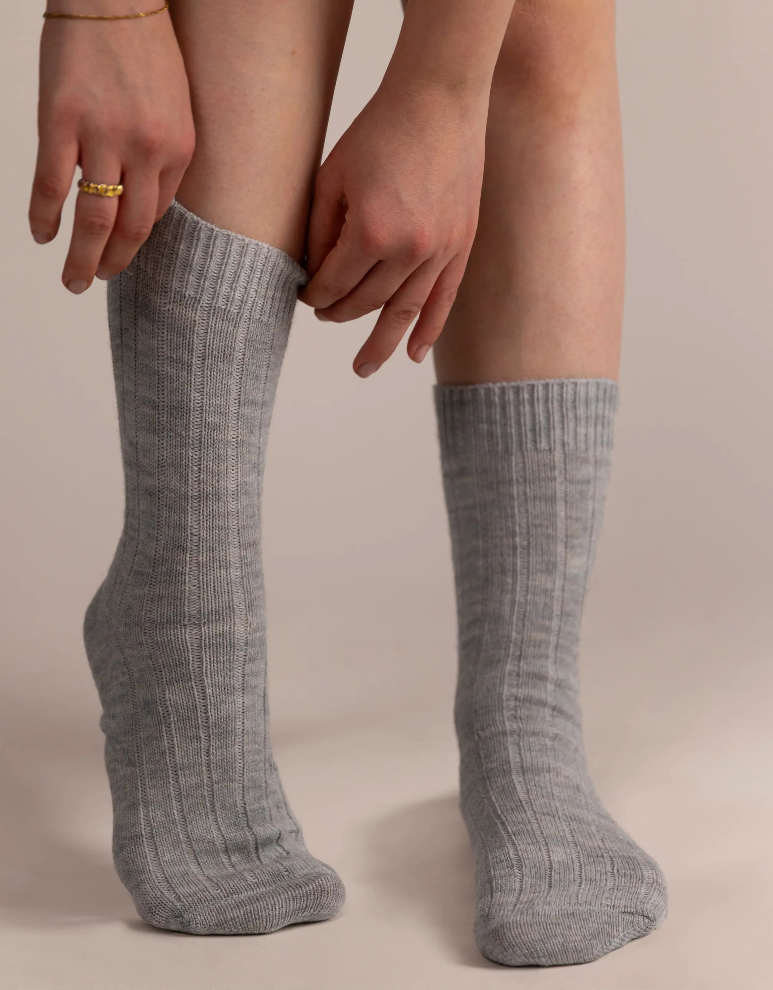 Person wearing gray knee-high socks on a beige background