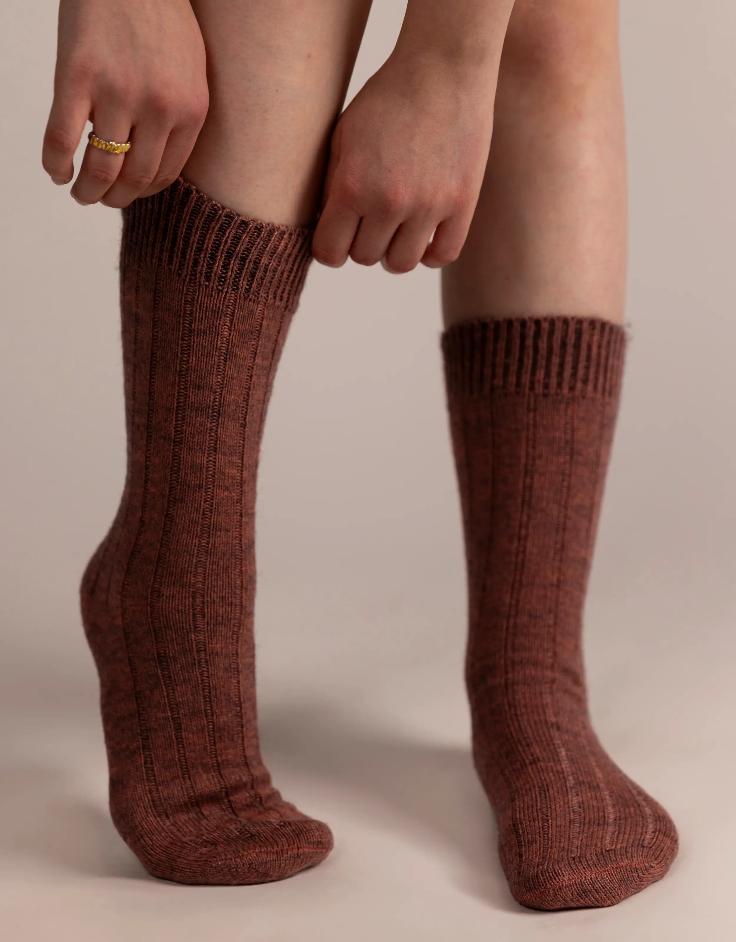 Bordeaux ribbed knee-high socks worn by a person on a beige background